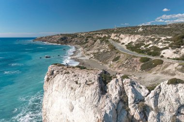 Turistler güneşli bir günde Afrodit 'in kayasındaki turkuaz denize hayran. Paphos İlçesi, Kıbrıs.