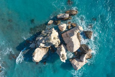 Turkuaz mavi okyanus suyu, Petra tou Romiou yakınlarındaki beyaz kayalara sıçrıyor. Paphos İlçesi, Kıbrıs