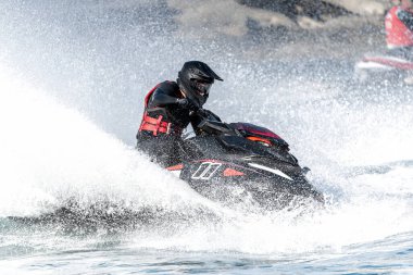 Profesyonel atlet yüksek hızda jet ski sürüyor, büyük bir sıçrama yaratıyor.