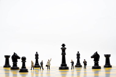 Merkezinde büyük bir satranç tahtasının üzerinde yürüyen minyatür insanlar, iş stratejisi ve taktik planlama kavramı