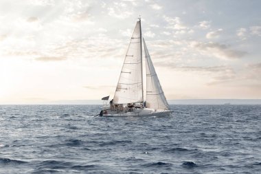 Günbatımında lüks bir yelkenliyle sakin ve sakin bir şekilde denize açılmak, okyanusun sakin sularını keşfetmek, deniz macerasının ve yatçılığın huzurlu doğasının tadını çıkarmak.