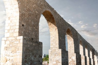 Antik kamare su kemeri bulutlu bir gökyüzüne karşı dimdik ayakta duruyor, larnaka 'da geçmişteki bir dönemin mimari hünerini sergiliyor.