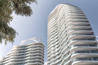 Güneşli bir günde mavi gökyüzüne karşı kıvrımlı balkonları olan iki modern apartman dairesi ya da apartman dairesi. Limasol, Kıbrıs