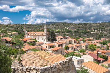 Lofou, a traditional village in Cyprus, showcasing its charming church and picturesque terraced hills under a beautiful sky. Limassol District clipart