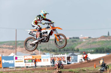 Agios Sozomenos, Kıbrıs - 11 Şubat 2024: Motokros sürücüsü arazi motosikletiyle havada süzülüyor, bir yarış sırasında becerilerini ve kararlılığını gösteriyor