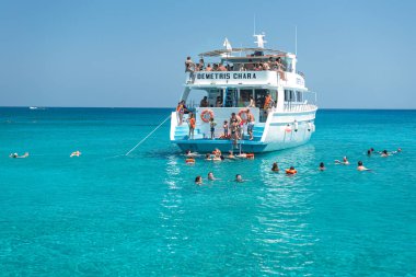 Ayia Napa, Kıbrıs - 23 Temmuz 2018: Turistler güneşli bir yaz gününde bir gezi teknesinden kristal berrak mavi Kıbrıs Denizi 'nde yüzüyorlar