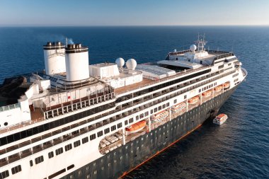 Güneşli bir günde, denizde cankurtaran botu olan büyük bir yolcu gemisi okyanusta yelken açıyor.