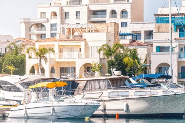 Güneşli bir yaz gününde, Limasol Marina 'daki modern konut binalarının yakınındaki limanda lüks yatlar yüzüyor. Kıbrıs