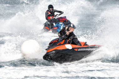 Jet ski 'deki profesyonel atlet şamandıranın etrafında keskin bir dönüş yapıyor ve bir sürü sprey üretiyor.