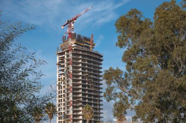 Kıbrıs 'ın Limasol şehir merkezinde modern bir gökdelende çalışan inşaat vinci