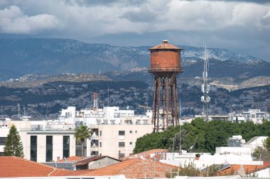 Eski, paslı su kulesi, arka planda Troodos dağları bulunan Kıbrıs 'ın Limasol kentinin siluetine hakim.