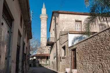 Eski taş evleri ve palmiye ağaçları olan Akdeniz veya Ortadoğu kasabasında camiye giden dar bir yol.