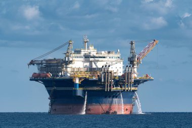 Deniz aşırı barınma platformu bulutlu bir günde denize su pompalıyor. Endüstriyel faaliyet ve kaynak çıkarma görüntüsü.