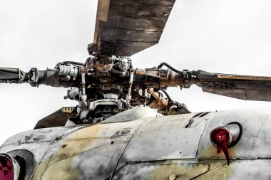 Askeri helikopterin pervane başı ve bıçakları gökyüzüne karşı duruyor, gücünü ve teknolojisini sergiliyor. Kokpitin ve pilotun yakın çekim görüntüsü uçuş ve tehlike hissini arttırır.