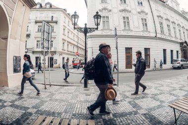 Prag, Çek Cumhuriyeti - 25 Mayıs 2017: Prag, Çek Cumhuriyeti 'nde bir kaldırım taşı sokakta yürüyen turistler, eski binaların ve sokak lambasının yanından geçtiler