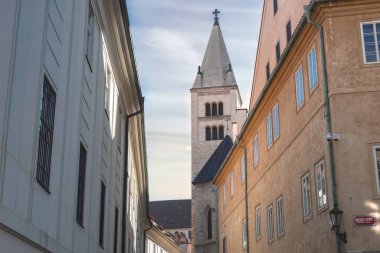 Çek Cumhuriyeti Prag 'ın dar bir caddesinde binaların üzerinde yükselen Aziz George Bazilika Kulesi