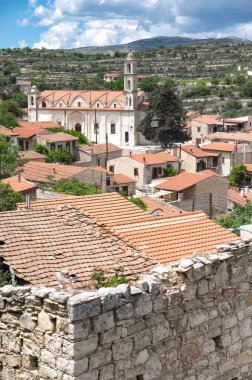 Lofou village, with its traditional stone houses and terracotta roofs, is dominated by the imposing presence of its church clipart