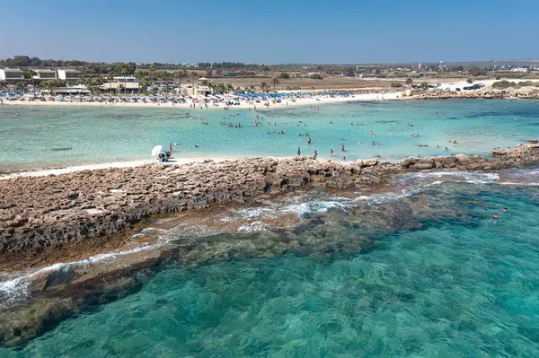 Turistler Ayia Thekla plajında güneşli bir yaz günü yüzüyor ve güneşleniyor. Ayia Napa, Kıbrıs