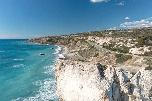 Uçurumun kenarında duran turistler, Kıbrıs 'ta popüler bir turizm beldesi olan Afrodit Kayası' nın (Petra tou Romiou) panoramik manzarasının keyfini çıkarıyorlar. Paphos Bölgesi