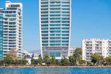 Kıbrıs Rum Kesimi 'nin Limasol kentinde gezinen turistlerle kıyı şeridinde duran modern gökdelen