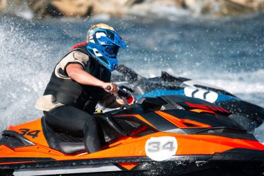 Bir jet ski yarışçısının dinamik görüntüsü yoğun bir odak ile çalkantılı nehir sularında geziniyor.