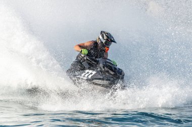 Yüksek hızda jet ski süren profesyonel bir sporcu büyük bir su sıçraması yaratıyor.