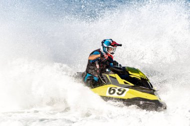 Profesyonel jet ski yarışçısı bir yarışma sırasında dalgaları yüksek hızda seyrederek büyük bir sıçrama yaratıyor.