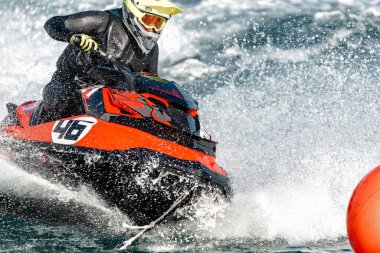 Pilot bir yarışma sırasında yüksek hızda jet ski sürüyor.