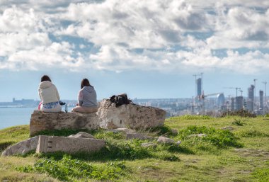 İki genç kadın, Amathus arkeoloji sahasından modern şehir Limasol 'un manzarasının keyfini çıkarıyorlar.