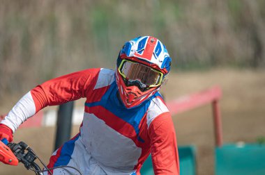 Motokros binicisi yarış sırasında toprak yolda hız yapıyor.