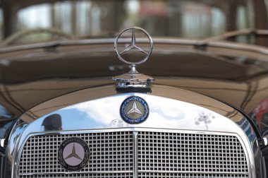 Larnaca, Cyprus- 12 Mayıs 2024: Krom kaput süsü klasik Mercedes-Benz üzerindeki bulutları yansıtıyor, klasik otomotiv zarafetini ve parlak metalik detaylarını vurguluyor