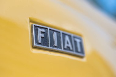 Larnaca, Cyprus- 12 Mayıs 2024: Krom Fiat amblemi parlak sarı klasik araba üzerinde parıldıyor, parlak metalik tasarım ile otomotiv mirasını vurguluyor