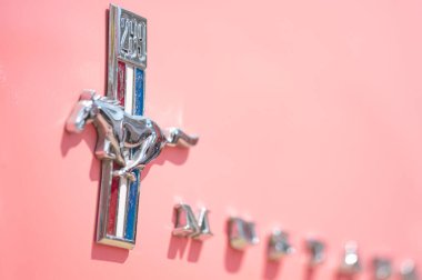 Larnaca, Cyprus- 12 Mayıs 2024: Pastel klasik aracın üzerinde parlayan Mustang krom at amblemi, retro otomotiv zarafetini simgeliyor.