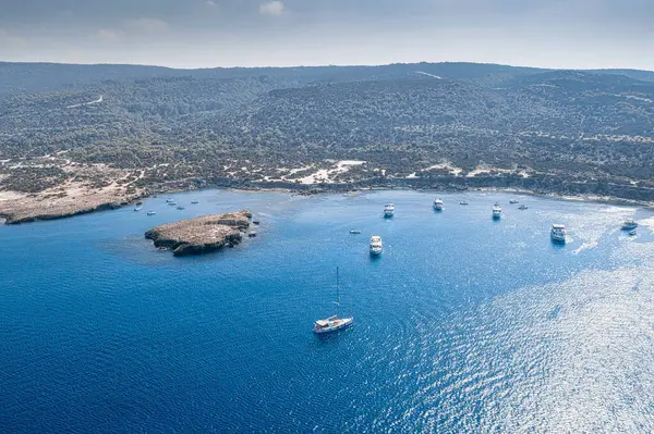Latchi yakınlarındaki Chrysochou Körfezi 'nin havadan görüntüsü, açık mavi sularda demirli yelkenliler ve motorlu tekneler, Kıbrıs' ın vahşi kıyı şeridiyle çevrili. Paphos Bölgesi