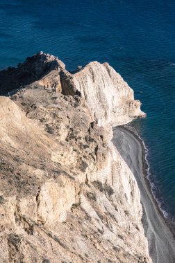 Cape Aspro 'nun beyaz kireçtaşı kayalıklarından geçen turistler, Kıbrıs' ta güneş ışığı altında uzanan masmavi sulara bakıyorlar.