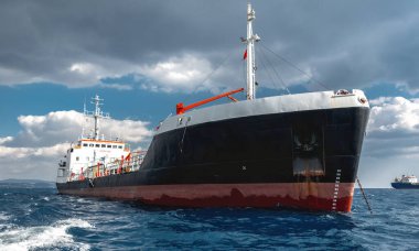 Kıbrıs 'ın Limasol kenti yakınlarındaki Akdeniz' de dramatik bulutlu bir gökyüzünün altında seyreden kargo gemisi.