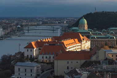 Buda Kalesi ve Özgürlük Köprüsü, Budapeşte 'de batan güneşin altın ışığıyla aydınlanır.