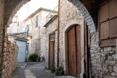 Taştan kemer yolu, Kıbrıs 'ın Pano Lefkara kentindeki dar sokaklar ve geleneksel evlerin resimli bir manzarasını çerçeveleyerek köyün mimari mirasını gözler önüne seriyor.