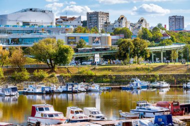 Belgrad, Sırbistan - 20 Eylül 2019: Mavi gökyüzü ve bulutlarla dolu güneşli bir günde rıhtımda demirlemiş teknelerle Belgrad şehir manzarası Sava nehrine yansıyor