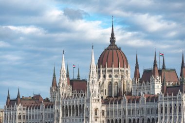 Budapeşte 'deki Macar parlamento binası Tuna nehrinin kıyısında bulutlu bir gökyüzünün altında görkemli bir şekilde duruyor.