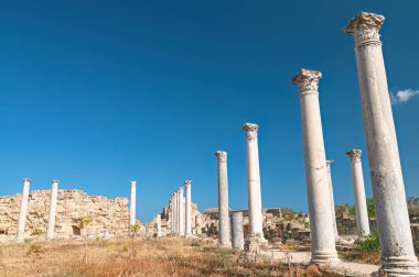 Kıbrıs Rum Kesimi 'nin Famagusta kentindeki parlak mavi gökyüzü altında antik Salamis kentinin mermer sütunları ve kalıntıları, tarihe büyüleyici bir bakış.