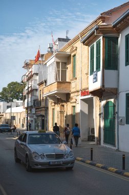 Lefkoşe, Kıbrıs - 31 Mayıs 2025: Kıbrıs Rum Kesimi 'nin Lefkoşe kentindeki Girne caddesinde kaldırımda yürüyen yayalarla birlikte gümüş rengi taksi