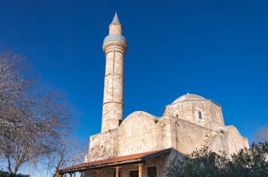 Djami Kebir camii, Kıbrıs 'ın Paphos kentindeki canlı mavi gökyüzüne karşı ayakta duruyor ve tarihi mimari ve kültürel önemini gözler önüne seriyor.