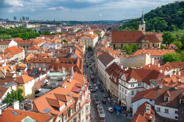 Güneşli bir günde, Çek Cumhuriyeti 'nin Prag kentindeki muhteşem turuncu çatıların, bir kilisenin ve dar bir caddenin havadan görünüşü.
