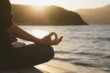 Woman in a yoga pose at sunset at the beach. Mindfulness and mental health concept.