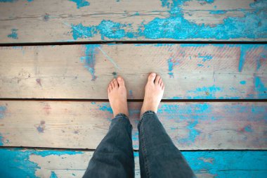 Woman leg's on wooden beach jetty. Barefeet on wooden planks. Unrecognizable person walking barefeet