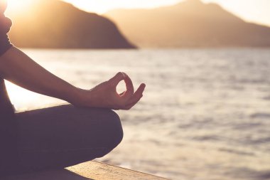 Woman in a yoga pose at sunset at the beach. Mindfulness and mental health concept.