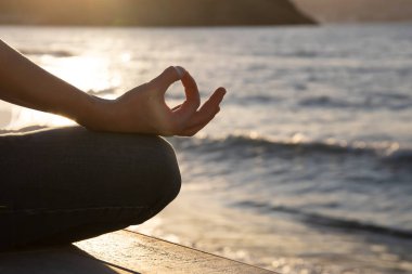 Woman in a yoga pose at sunset at the beach. Mindfulness and mental health concept.