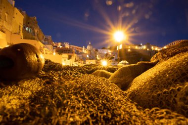 Fishing nets the Port of Corricella with lots of colorful houses after sunset in Procida Island, Italy.