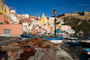 View of the Port of Corricella with lots of colorful houses on a sunny day in Procida Island, Italy.